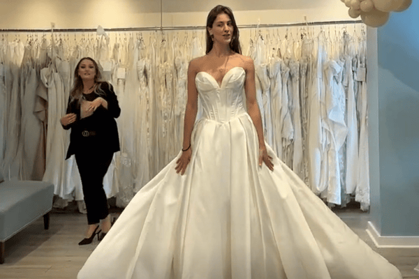 A bride with her stylist trying on her wedding gown