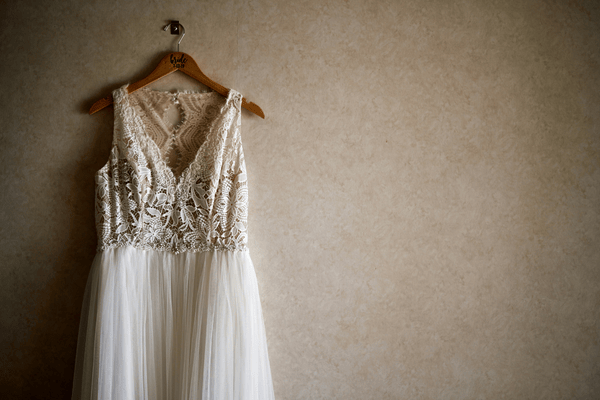 Lace wedding dress with embroidered bodice and soft tulle skirt hanging on a wooden hanger