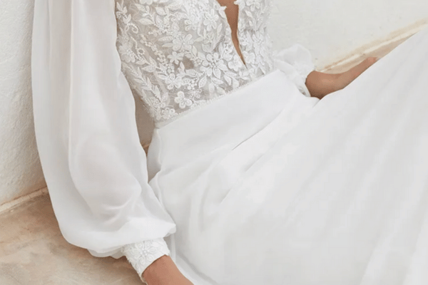 A woman in a chiffon wedding dress sitting on the floor while