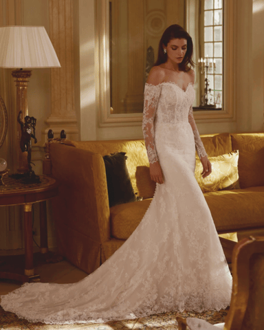 a bride in her fit and flare wedding gown in a vintage designed living room staring at the floor 