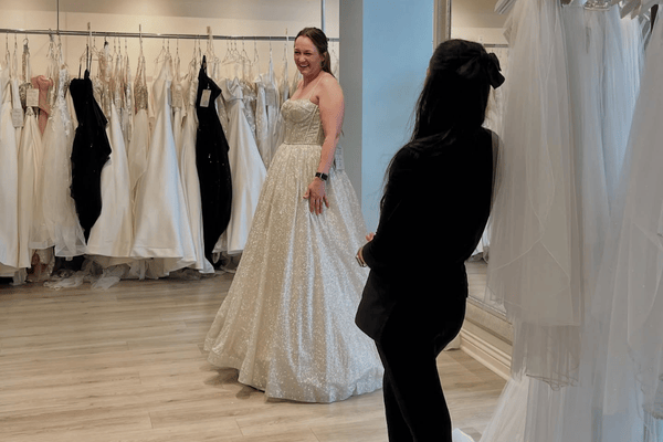 A bride trying on her wedding gown while her stylist watch her twirl
