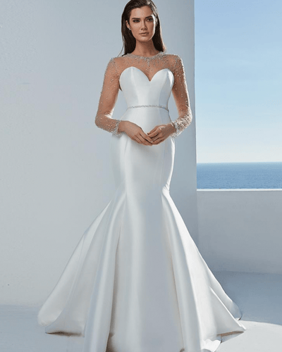 A woman in a white mermaid wedding dress with beaded long sleeves and a heart-shaped neckline. 