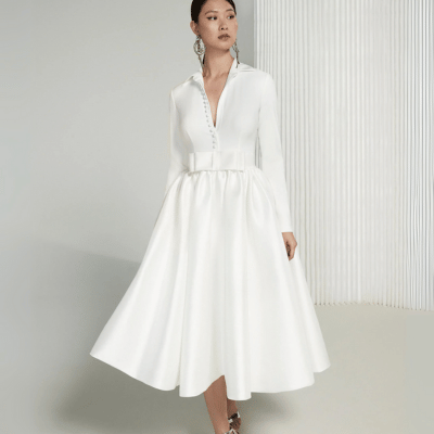 A bride wearing a tea-length wedding dress with a collar and long sleeves, showcasing an elegant and unique look. Perfect for those exploring a wedding dress style guide or looking to match their bridal personality style, this gown offers a fresh take on classic and unique wedding gowns..