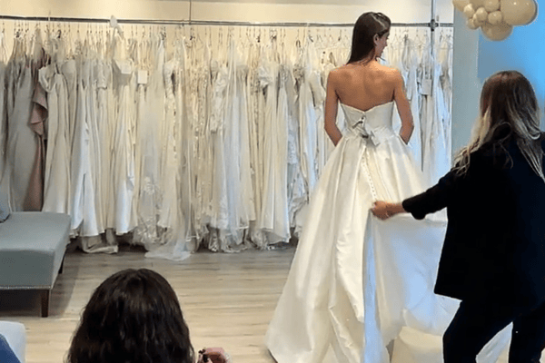 a bride trying on her wedding dress in front the wedding rack