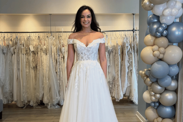 Bride wearing an off-the-shoulder lace wedding dress in a bridal boutique