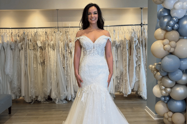 Bride wearing an off-the-shoulder lace mermaid wedding dress in a bridal boutique