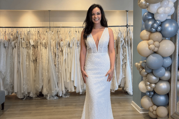 Bride wearing a fitted lace wedding dress with deep V neckline in a bridal boutique