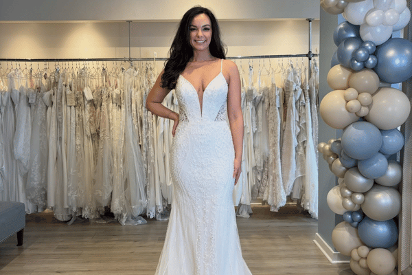 Bride trying on a fitted lace wedding dress with spaghetti straps in a bridal shop