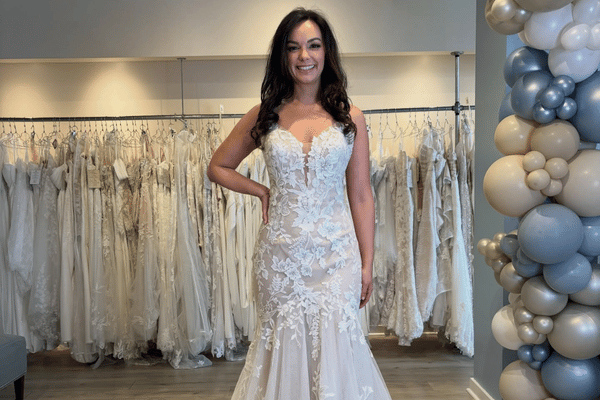 Bride wearing a fitted floral lace wedding dress with deep V neckline in a bridal boutique