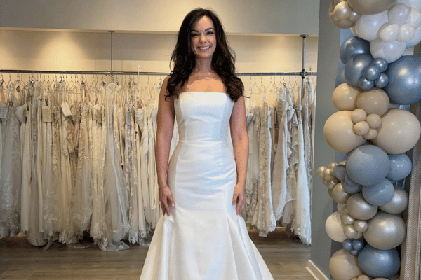 Bride wearing a strapless fitted satin wedding dress in a bridal boutique
