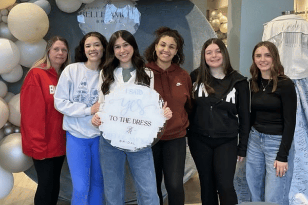 Bride posing with friends and family at Belle Amour Bridal while holding an &ldquo;I Said Yes to the Dress&rdquo; sign after her bridal appointment.