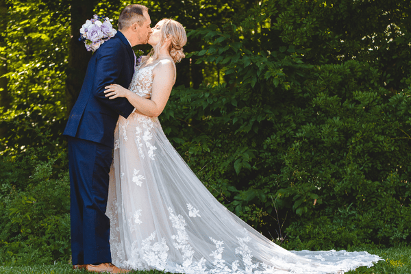 Groom and her bride holding her bouquet kissing