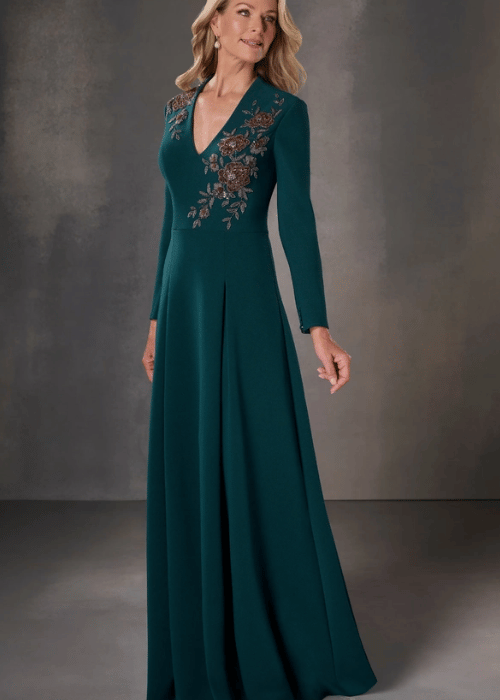 Long sleeve emerald green mother of the bride gown with floral embellishment and a flowing A-line silhouette.