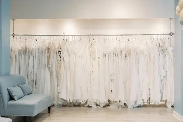 Wedding gowns displayed on a long rack inside a bridal boutique