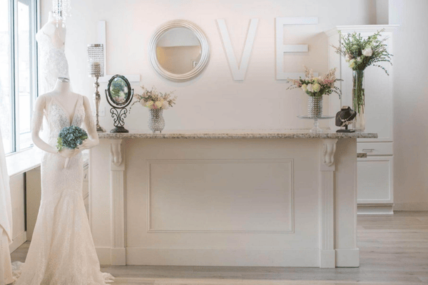 A wedding dress mannequin next to a white counter, with 'LOVE' letters on the wall—a perfect setting for sharing helpful bride shopping tips as you plan your big day.
