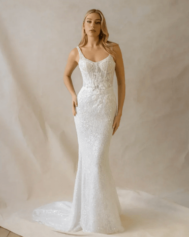 A woman in a stunning white sheath bridal gown with a fitted silhouette and embellishments. 
