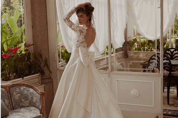 A stunning example for a wedding dress style guide, this unique bridal gown features a lace bodice with long sleeves and a large bow at the back. Perfect for showcasing bridal personality styles, it’s an ideal choice for those seeking unique wedding gowns that make a statement.
