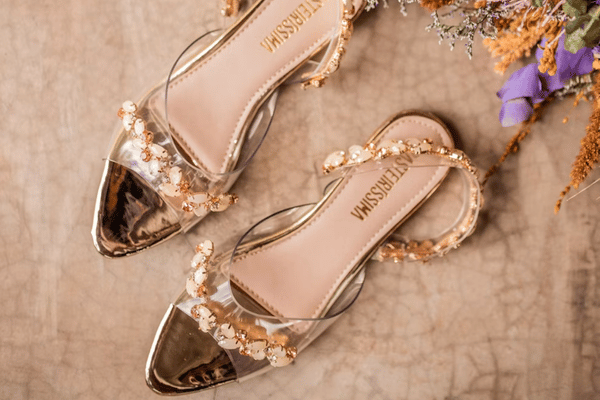 Elegant gold bridal sandals featuring pearl embellishments and transparent straps for a wedding dress.