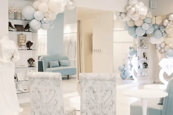 Interior of a bridal boutique with wedding gowns, mirrors, seating, and bridal accessories