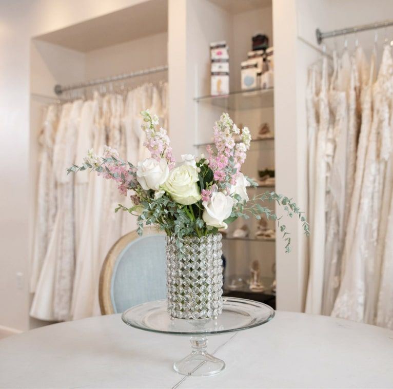 Bridal store image with dresses and flowers on a table top